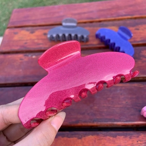 Detail of rose red glitter acetate hair claw clip with colorful sparkling finish