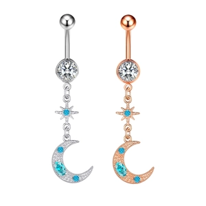 Detail of silver and rose gold belly rings featuring sparkling blue star and moon charms