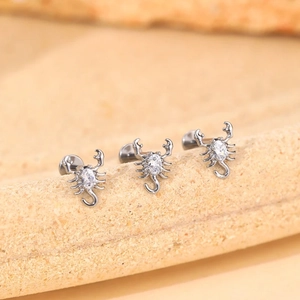 Vue détaillée de trois piercings scorpion en argent avec zircon blanc sur liège