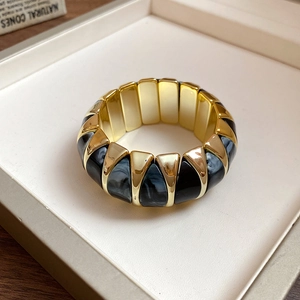 Macro view of wide elastic bracelet with gold trapezoid blocks and marble resin texture