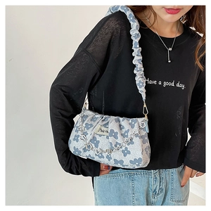 Close-up of light blue floral handbag with cloud-pleat design and silver flower chain detail