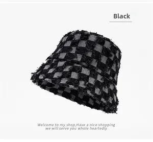 Detail shot of black and grey checkered bucket hat with frayed edges and raw denim texture
