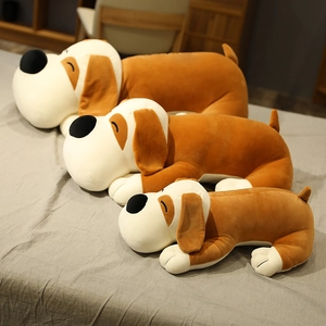 Three sizes of plush lying dog pillows in brown and beige on a cozy gray bed