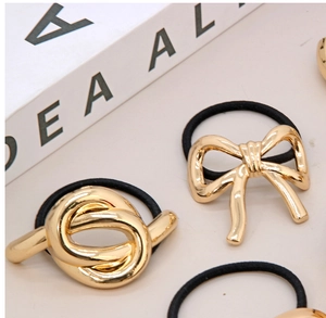 Macro view of knot and bow gold metal charms on high-elastic black hair ties