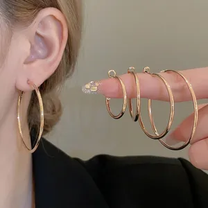 Golden geometric hoop earrings in four sizes displayed on hand with a sleek metallic finish