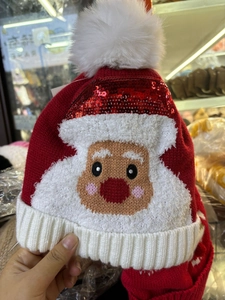 Détail du bonnet de Noël en tricot rouge et blanc avec paillettes et pompon blanc