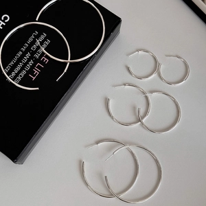 Set of four silver round hoop earrings in different sizes on a light gray surface