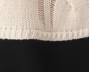 Macro detail of beige ribbed knit texture and premium stitching on the dress cuff