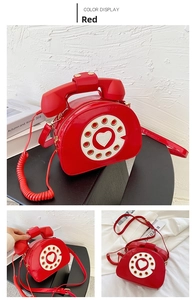 Detail of red patent leather crossbody bag with vintage telephone dial and handset handle
