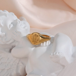 Detailed view of a gold signet ring with engraved flower pattern on a statue