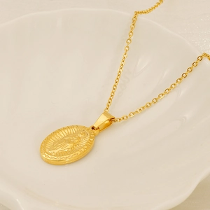 Macro detail of gold-plated Saint Jude Thaddeus pendant necklace on shell tray