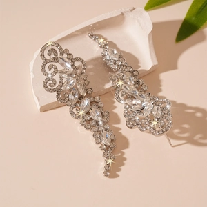 Sparkling crystal leaf earrings featuring silver tassel drop design on stone pedestal