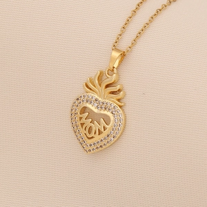 Macro shot of gold heart pendant featuring MOM inscription and sparkling stone border