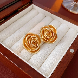 Close-up of golden vintage rose flower stud earrings in a wooden jewelry gift box
