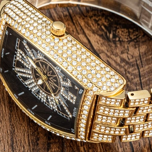 Close-up of gold iced-out tonneau watch featuring a compass-style dial with crystal accents