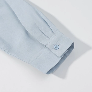 Detail shot of light blue linen shirt cuff featuring a matching button and neat stitching