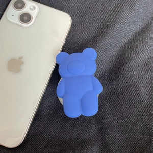 Macro detail of blue 3D matte bear phone socket grip on denim background