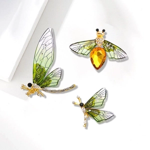 Detailed top view of gold insect brooches with green and yellow crystal wings