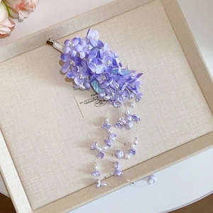 Close-up of purple acrylic flower hair clip with pearl tassels and floral details
