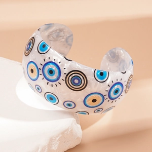 Detail of white acrylic evil eye open bangle showing geometric design on stone tray