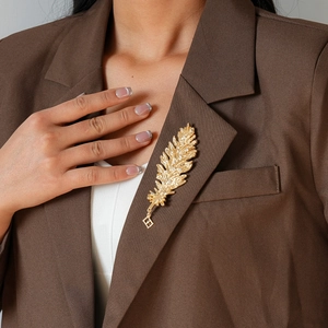 Detail of a vintage gold feather brooch with rhinestones on a brown blazer lapel
