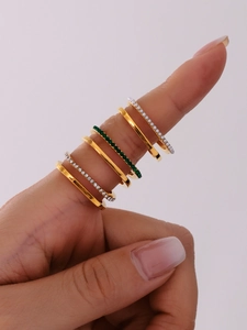 Detail of six-piece gold ring set with green zircon and pearl layers worn on finger