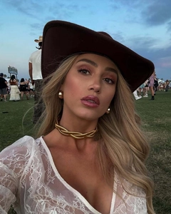 Dettaglio di girocollo dorato a spirale e cappello da cowboy marrone con top in pizzo