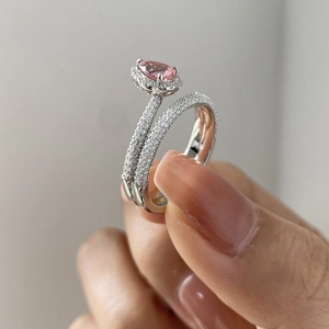 Elegant silver ring set featuring a pear-cut pink stone and micro-paved eternity band