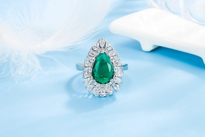 Close-up of a pear-shaped emerald ring with marquise-cut zircon stones on a silver band
