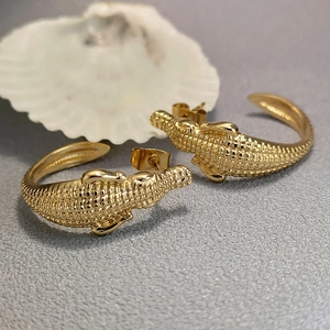Pendientes de aro de cocodrilo dorados con textura de escamas en fondo oscuro