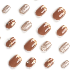 Short brown false nails with silver glitter, golden floral accents and rhinestones