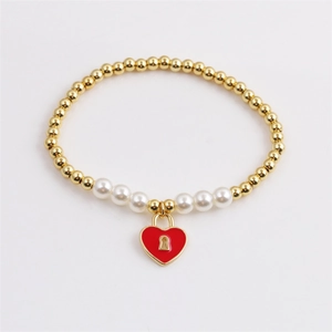 Elegant gold beaded bracelet with white pearls and a red enamel heart lock pendant
