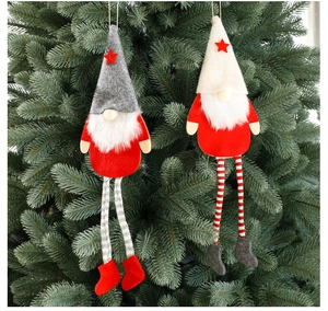 Detail of two Christmas gnome ornaments with long legs hanging on green pine tree branches