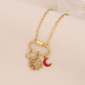 Close-up of gold star and moon charms with red enamel and crystals on a necklace