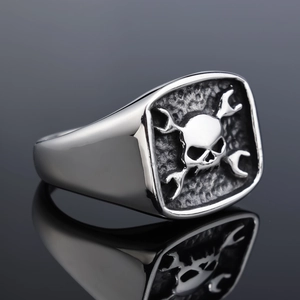 Detail of punk motorcycle style ring featuring 3D skull and wrench emblem on square face