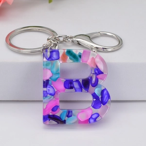 Macro shot of letter B resin keychain with colorful stones and silver metal ring