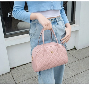 Détail du sac à main matelassé rose avec emblème de fleur dorée tenu par un mannequin