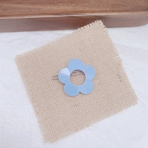Detailed view of light blue flower hair clip on rustic burlap and textured background