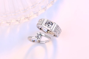 Close-up of couple's silver rings featuring Greek key pattern and sparkling square stones
