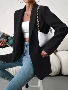 Gros plan d'un blazer noir cintré avec sac blanc effet croco et jean pour un look chic