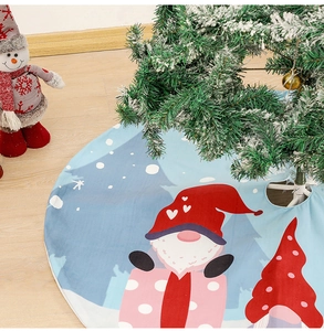 Close-up of blue Christmas tree skirt with red gnome prints on wooden floor background