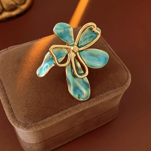 Detailed close-up of a vintage teal enamel flower ring on a brown velvet jewelry box