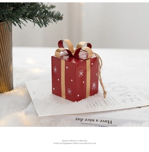 Detail of red Christmas gift box ornament with gold ribbon and white snowflake patterns