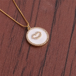 Detailed view of a gold-plated necklace featuring a white round lip-patterned pendant