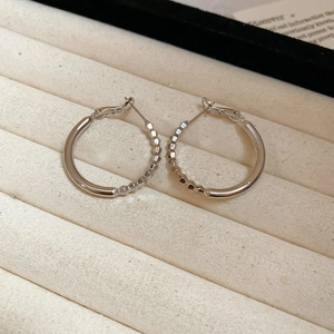 Detailed view of silver hoop earrings with smooth and faceted textures on a velvet tray