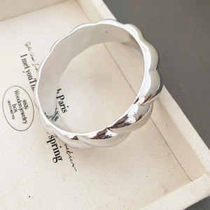 Macro shot of silver minimalist wavy ring with a mirror-polished finish on a jewelry tray