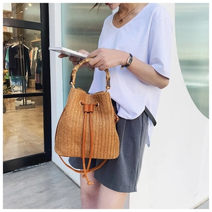 Straw bucket bag with bamboo handle and leather drawstring closure, shown in detail