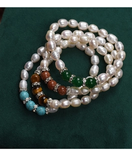 Macro shot of freshwater pearl bracelets with turquoise and tiger eye stones on velvet