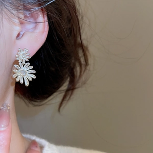 Close-up of elegant white daisy flower earrings with gold accents on model ear