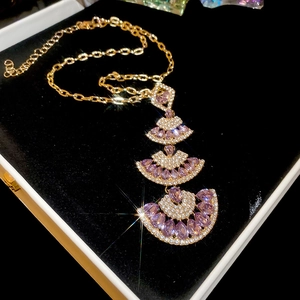 Detail of gold fan-shaped pendant with purple stones on black velvet box
